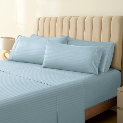 a bed with a light blue sheet and pillows